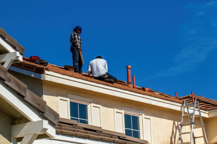Travailleurs réparant le toit d'une maison.